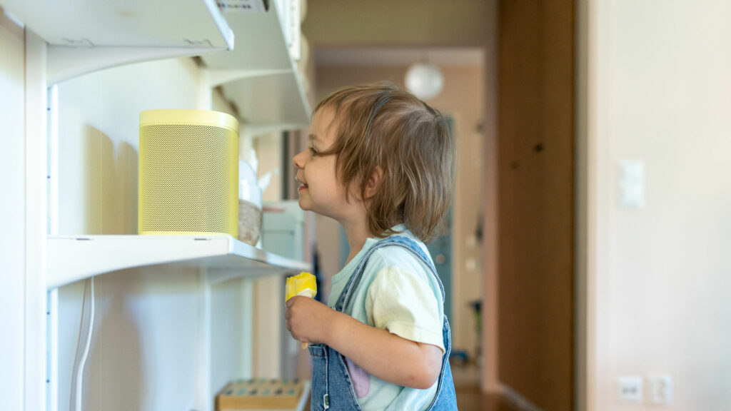 Liten pojke äter glass och talar med en smart högtalare.